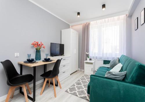 a living room with a green couch and a table at Rybacka 48 - Twoje miejsce wypoczynku, domki, studia, apartamenty, rowery, hulajnogi in Jantar