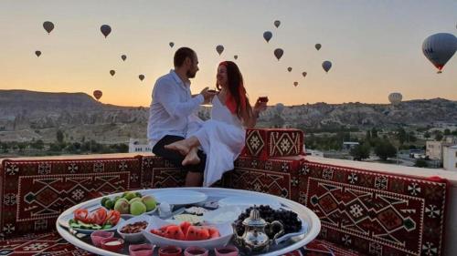 a man and woman sitting on a balcony with a table of food at Katapa Stone House in Goreme