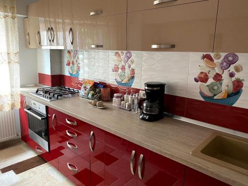 una cucina con armadi rossi e piano di lavoro di Apartament cozy a Drăgăşani