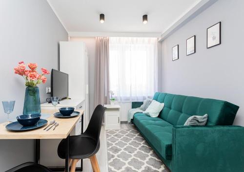 a living room with a green couch and a table at Rybacka 48 - Twoje miejsce wypoczynku, domki, studia, apartamenty, rowery, hulajnogi in Jantar