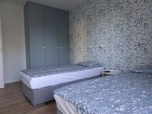 two twin beds in a bedroom with a wall at VIP apartament w parku nad Zatoką in Puck