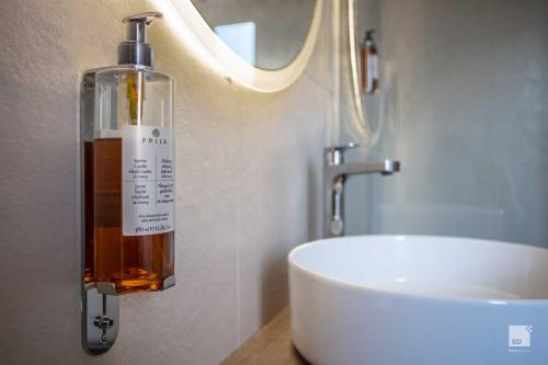 a bottle of alcohol on a wall next to a sink at Hotel Regina Elena 57 & Oro Bianco SPA in Rimini