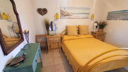 a bedroom with a yellow bed and a mirror at Sa Prama Pineta in Orosei