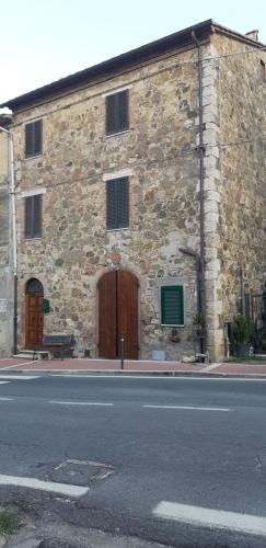 a stone building with a wooden door and a bench on a street at Appartamenti di Luca&Sara in Le Piazze