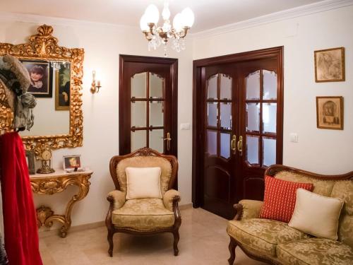 sala de estar con 2 sillas y espejo en Belvilla by OYO Preciosa casa en Sevilla, en Sevilla