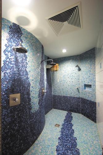 y baño con ducha y mosaicos azules. en Panorama-Hotel am See, en Neunburg vorm Wald