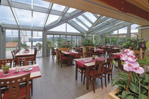 un restaurante con mesas, sillas y ventanas en Panorama-Hotel am See, en Neunburg vorm Wald