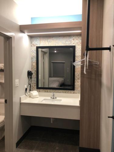 a bathroom with a sink and a mirror at Hotel Solara I-45 & Hobby Airport Houston in Houston