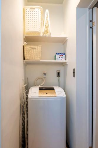 a washer and dryer in a laundry room with shelves at Nishihan in Kyoto