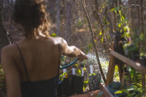 a woman is spraying herself with a hose at New Ruins Off-The-Grid SuperAdobe Domes with Pool in San Francisco de Abajo