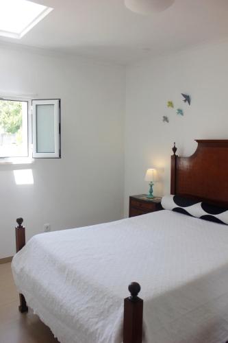 a bedroom with a large white bed with a window at Casinha da Andorinha - Ericeira in Ericeira