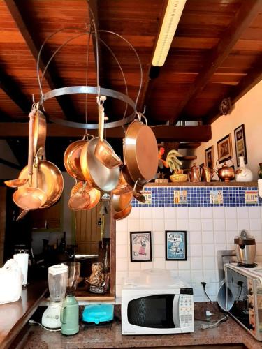 een keuken met koperen potten en pannen die aan een kroonluchter hangen bij Casa no Centro Histórico de Pirenópolis in Pirenópolis