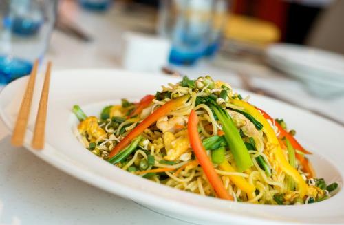 a plate of food with noodles and vegetables on a table at ibis Bengaluru Hosur Road - An Accor Brand in Bengaluru