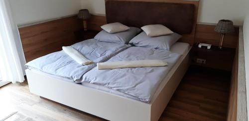 Una cama con sábanas blancas y almohadas. en Deichresidenz Büsum en Büsum