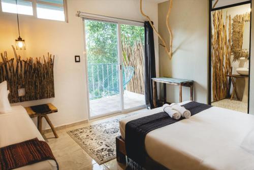 a bedroom with a bed and a window with a balcony at LA TULUMEÑA Boutique Hotel in Tulum