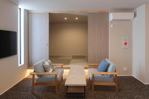 大阪市にあるコティ・ソポ ユニバーサル ベイ2byリエゾンの椅子2脚、テーブル、テレビが備わる客室です。