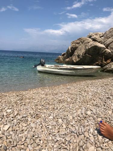 a boat on a rocky beach next to the water at Apartments House Filipović in Makarska
