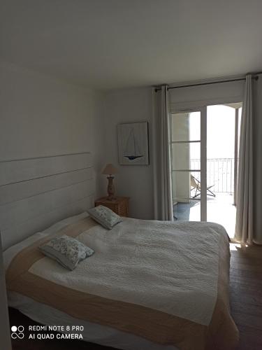 a bedroom with a bed and a sliding glass door at Port rive gauche Oyat in Marseillan