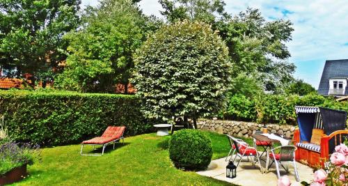 un jardín con sillas, mesas y un seto en 4-ZIMMER-FERIENWOHNUNG DEICHWIESE -Westerland-Sylt - Garten - Terrasse - 3 Schlafzimmer - 2 - 5 Pers, en Westerland