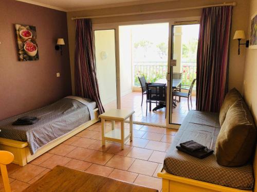 Cet appartement comprend une chambre avec deux lits et un salon avec un balcon. dans l'établissement Appartement de standing face à la baie de St-Tropez, vue mer, jardin et piscine., à La Garonnette-Plage