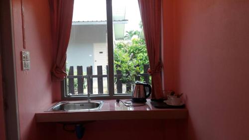 eine Küche mit einem Waschbecken und einem Fenster in der Unterkunft Wansawang Homestay in Pran Buri