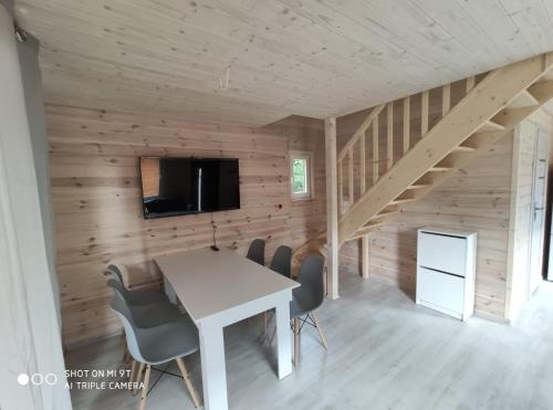een eetkamer met een tafel, stoelen en een tv bij LEŚNA OSTOJA in Rewal