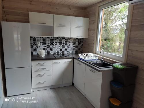 een keuken met witte kasten, een gootsteen en een raam bij LEŚNA OSTOJA in Rewal
