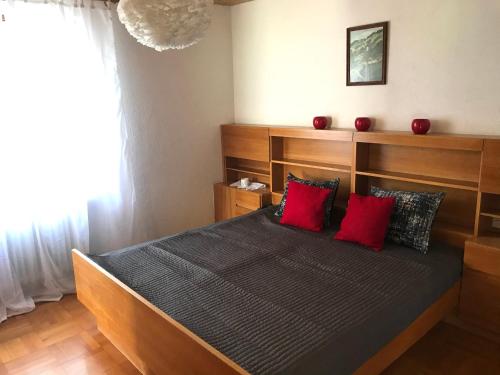 una camera da letto con un grande letto con cuscini rossi di Kleine Ferienwohnung am Rande der Wildnis a Sibratsgfäll