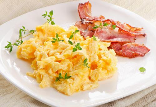 a plate of scrambled eggs and bacon on a table at Pannonia Hotel in Sopron