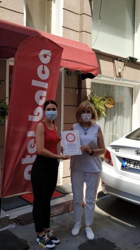 two women standing next to a sign holding a box at Hotel Balca in Izmir