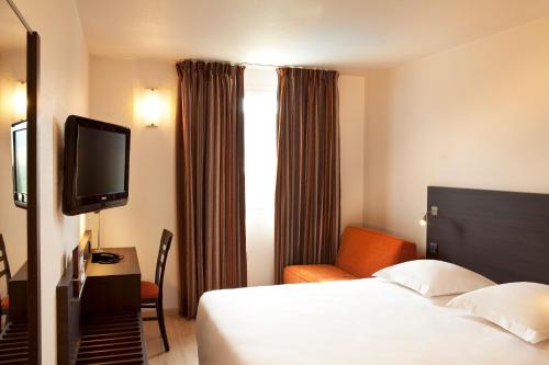 a hotel room with a bed and a television at Escale Oceania Aix-en-Provence in Aix-en-Provence