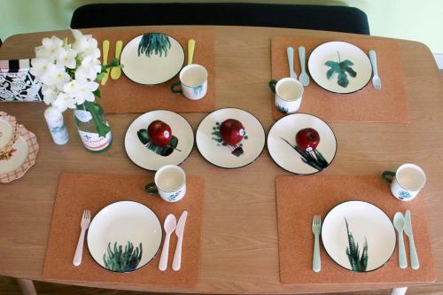 a wooden table with plates and cutlery on it at Baan Rub Lom by Jane in Pak Chong