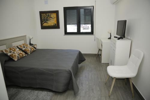 a bedroom with a bed and a tv and a chair at Casa da Praça in Ponte de Sor