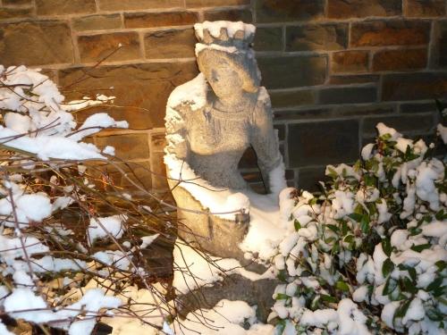 a statue sitting in the snow next to a brick building at Romantik Waldhotel Mangold in Bergisch Gladbach