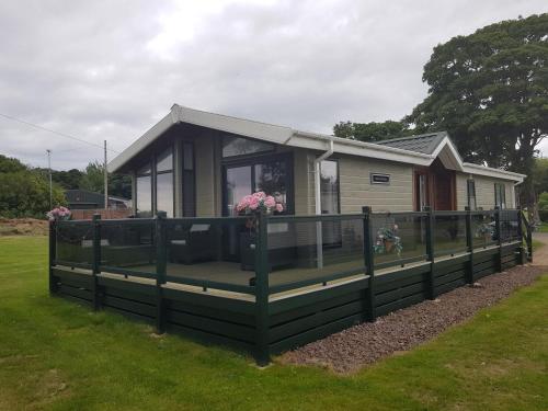 a tiny house with a large deck on the grass at Sea views, fabulous modern lodge in Port Seton