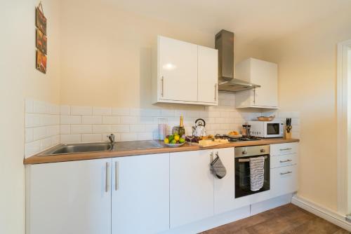 una cocina con armarios blancos y fregadero en 3 Bedroom-5 Beds Newland Ave King's Palace Leisure-Contractor-Heart of Hull Amenities en Hull