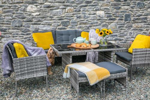 a patio with a table and chairs and a stone wall at The Beeches in Killarney