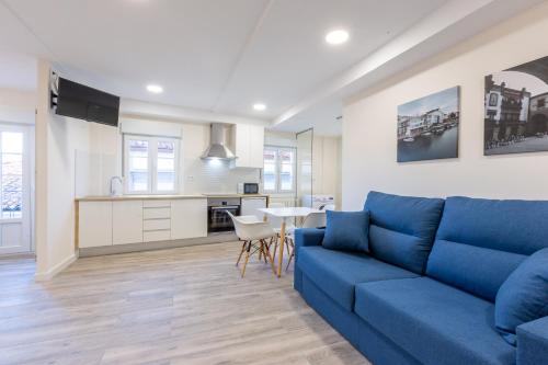 a living room with a blue couch and a kitchen at MIRADOR DE LA MURALLA in Betanzos