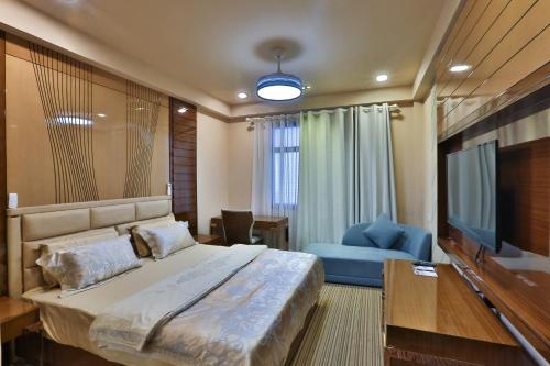 a bedroom with a large bed and a television at Hotel Fun Residency by Antra Group in Ahmedabad