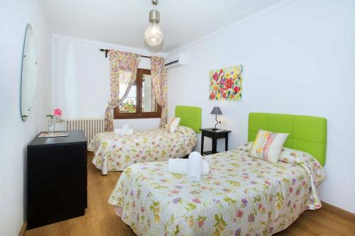 two beds in a room with green and white at Villa Tomeu by Sealand Villas in Port de Pollensa