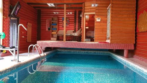 una piscina en una casa roja con un banco al lado en Luxury apartments with pool and sauna in the Villa, en Chernivtsi