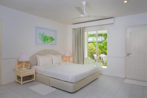 a white bedroom with a bed and a window at Equator Village Resort in Gan