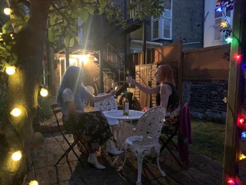 two women sitting at a table in a garden at night at Albert's Rest in Ramsgate