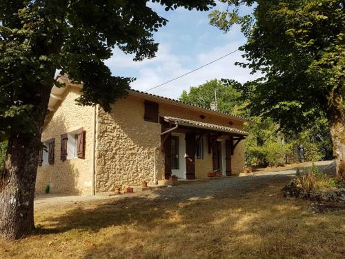 a stone house with a tree in front of it at Petite maison du Tertre in Baneuil