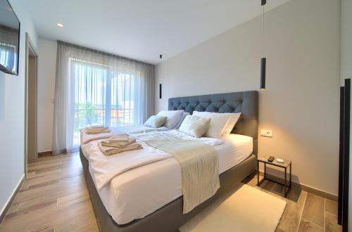 duże łóżko w pokoju z dużym oknem w obiekcie Apartments Vista Deluxe w mieście Malinska