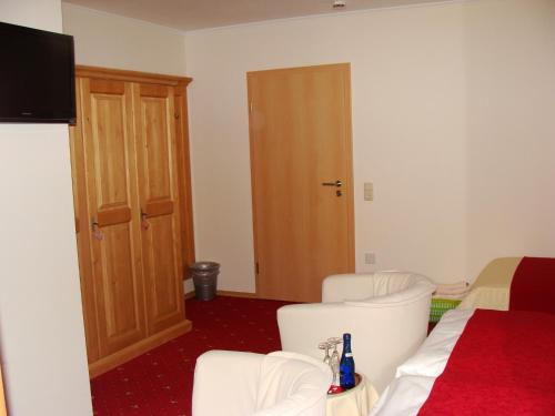 a room with two white chairs and a television at Drei Tannen in Bodenmais