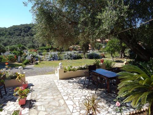 a patio with a table and chairs in a garden at Vanilla House Paleokastritsa in Paleokastritsa