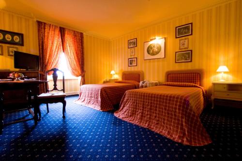 two beds in a hotel room with yellow walls at Il Sole Di Ranco in Ranco