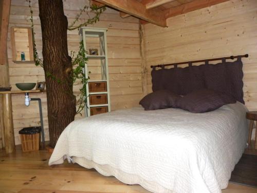 1 dormitorio con 1 cama junto a un árbol en Domaine de la Boere, en Beaulieu-sous-la-Roche