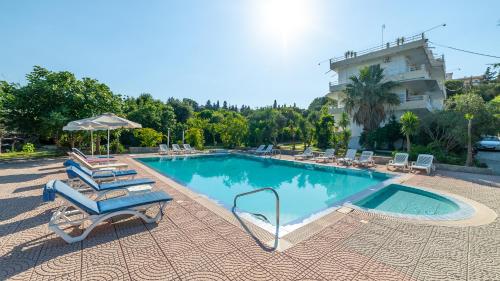 a swimming pool with lounge chairs and a building at Artemis Studios - Pool and garden in Koskinou